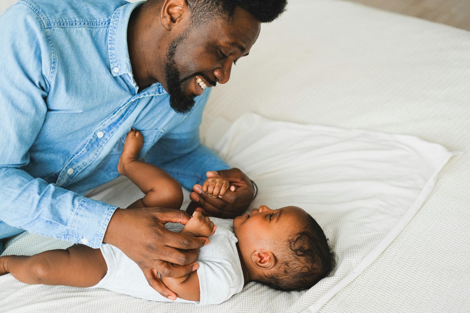 Loving father playing with his baby on a cozy indoor bed, sharing smiles and affection.
