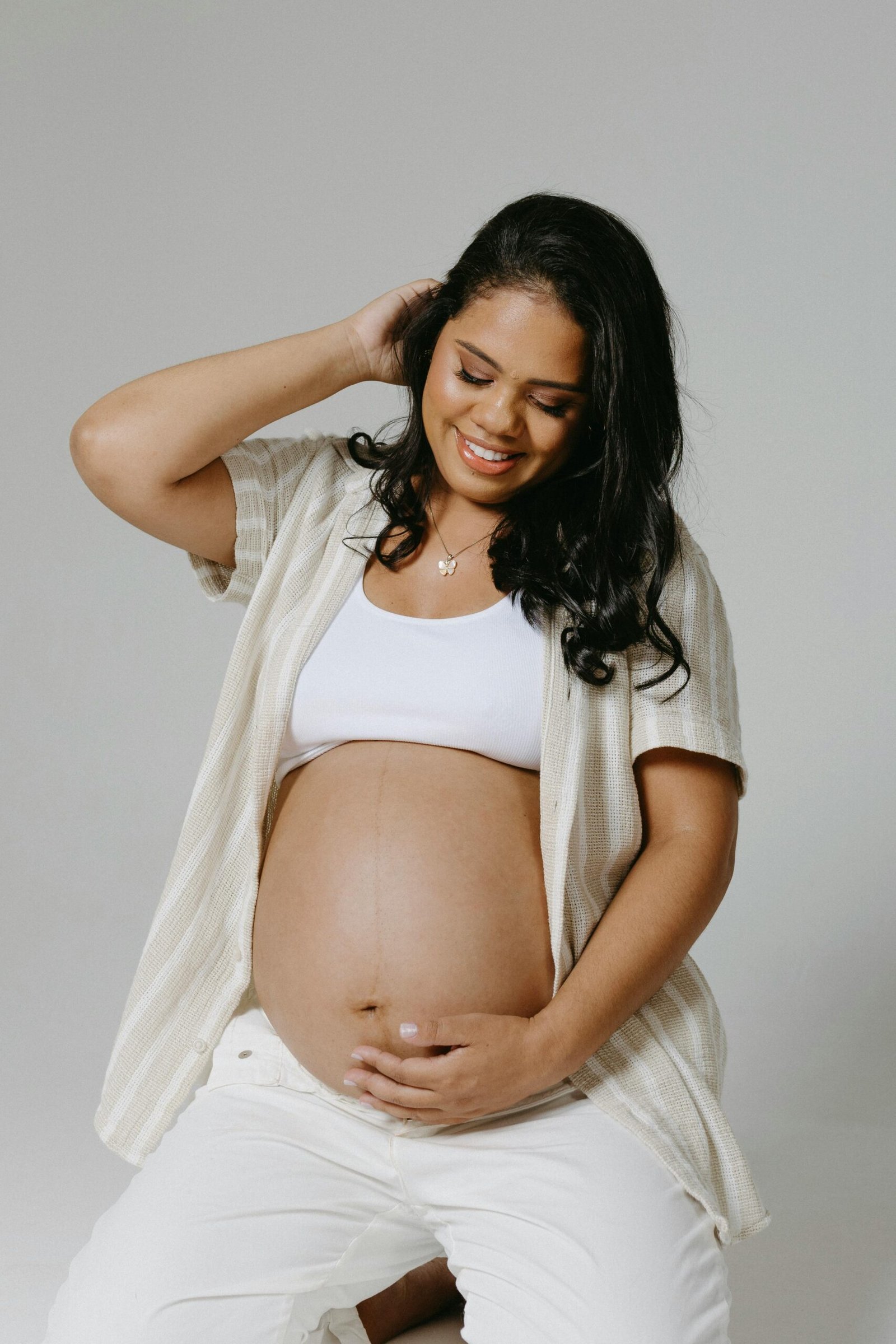 A joyful pregnant woman poses in a studio, exuding warmth and beauty.